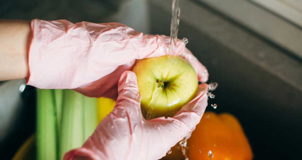 donna con guanti lava frutta in periodo di covid19